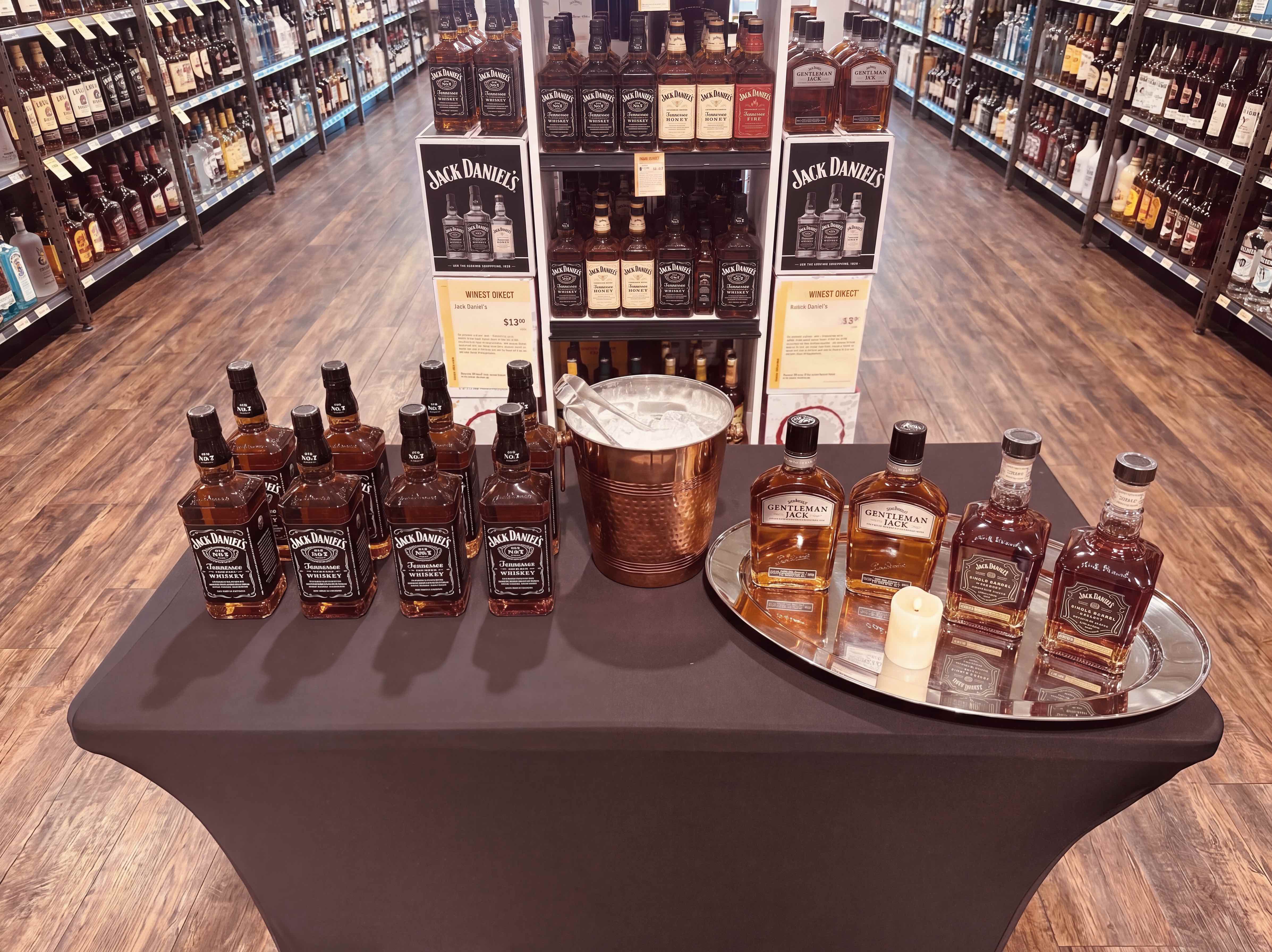 A fully merchandised whiskey tasting table set inside a liquor store aisle
